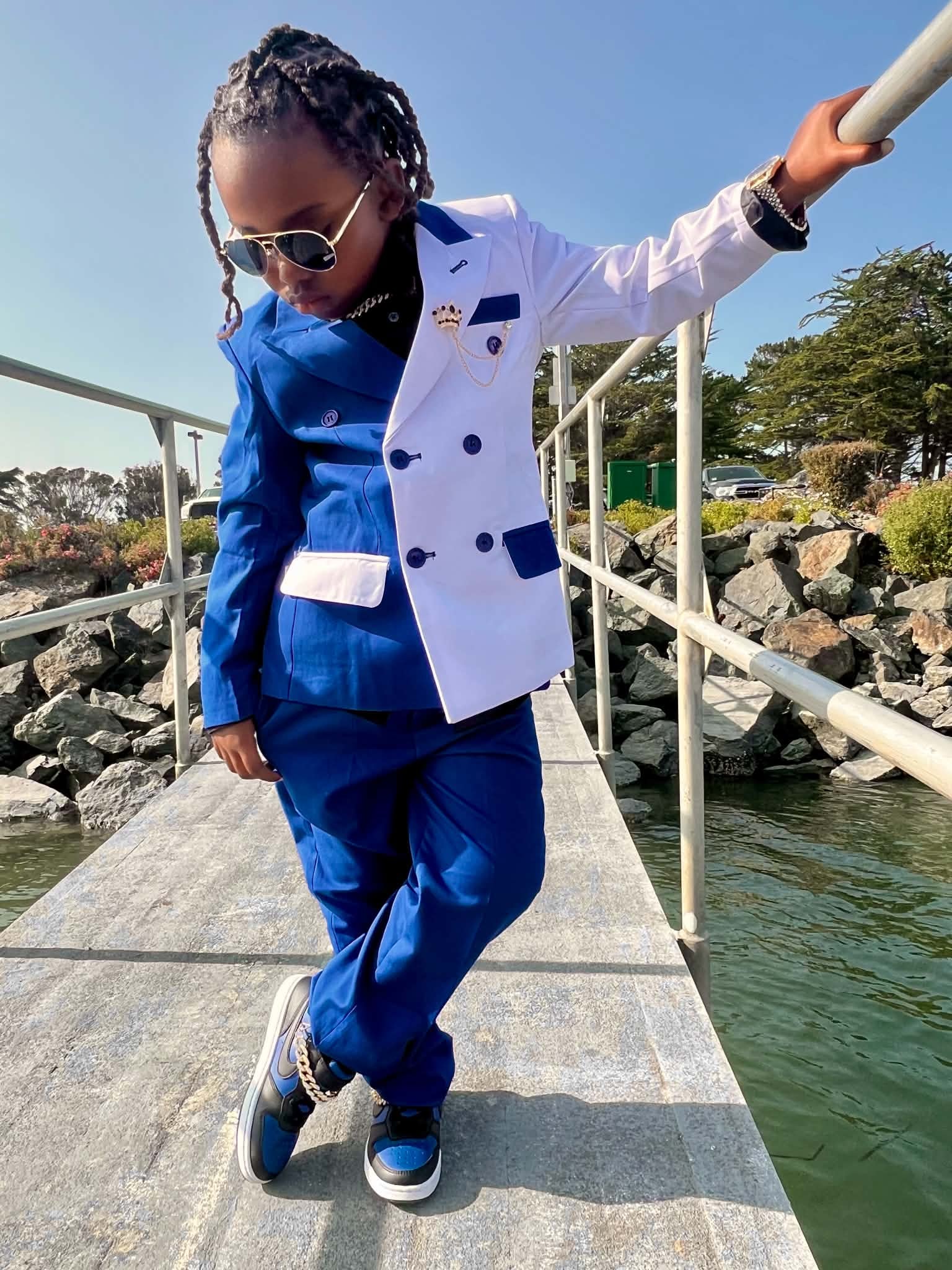 Child in a blue and white suit on a waterfront walkway