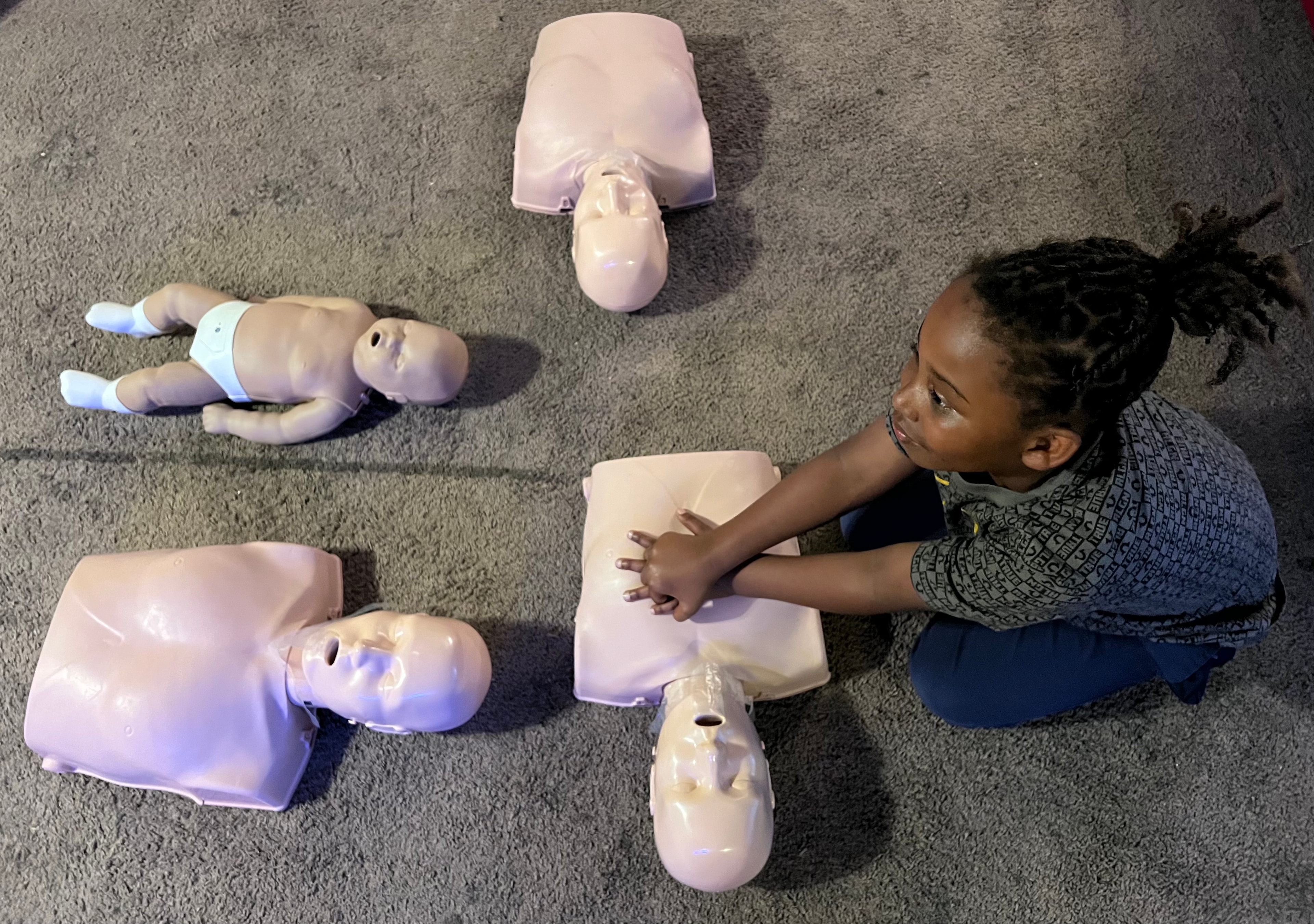 Child practicing CPR with training mannequins