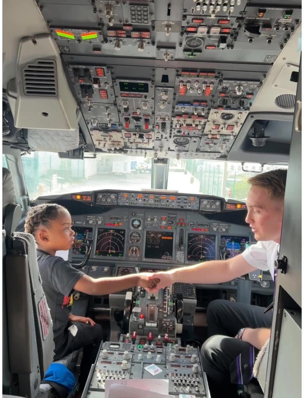 Child shaking hands with a pilot during a cockpit visit