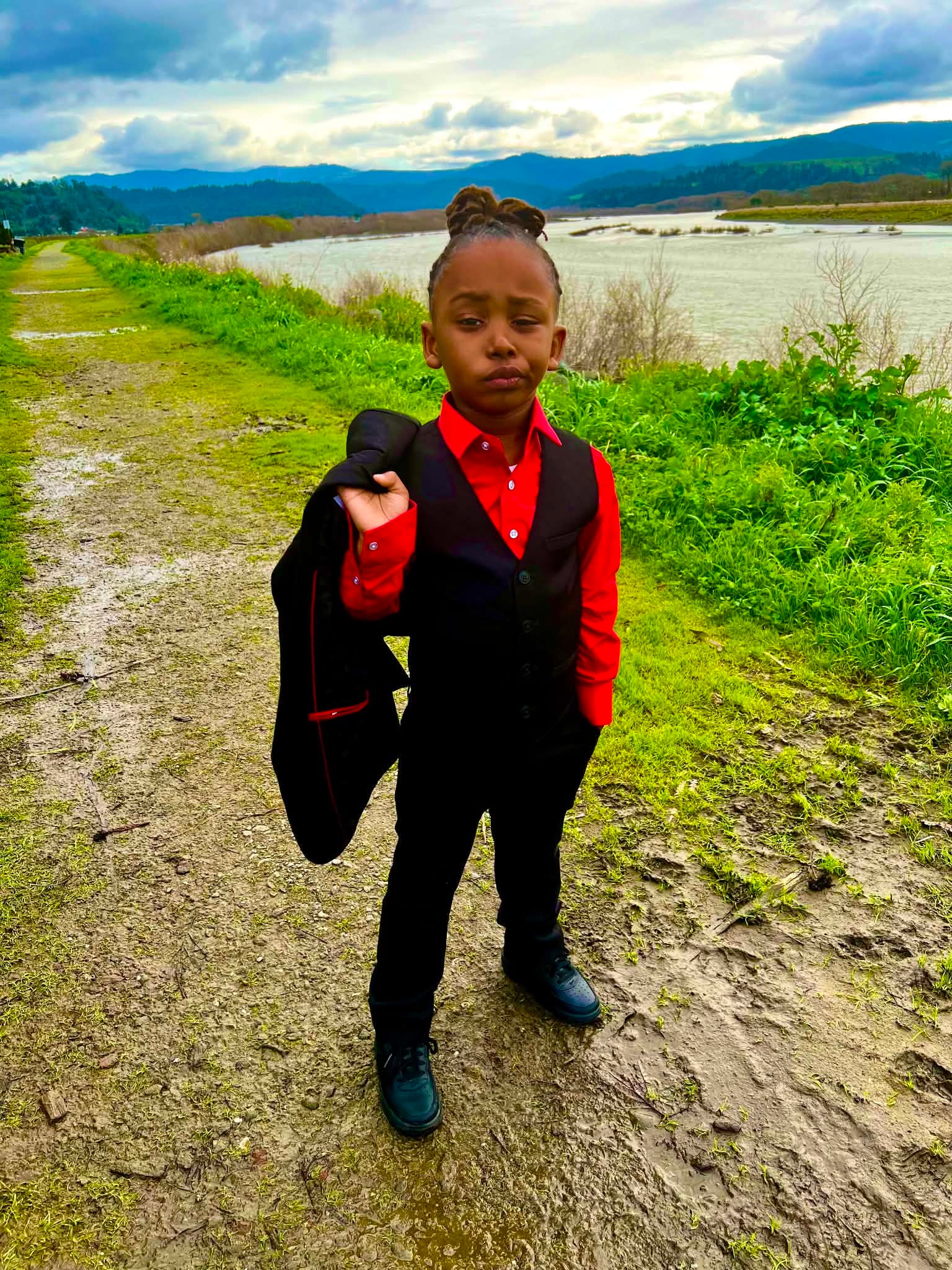 Child dressed up beside a riverside landscape