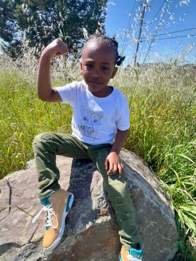 Child proudly flexing during an outdoor adventure