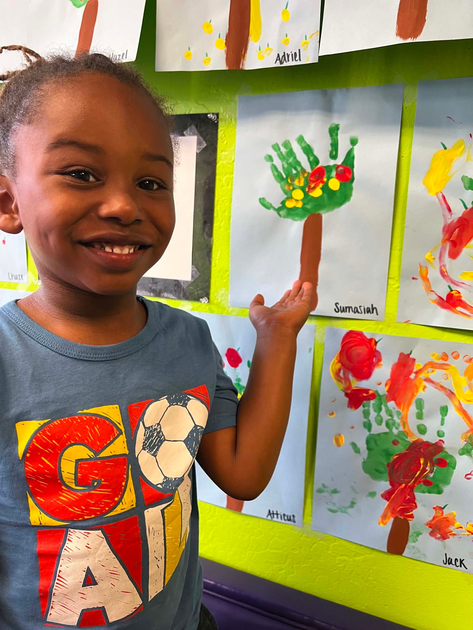 Child proudly presenting colorful classroom artwork