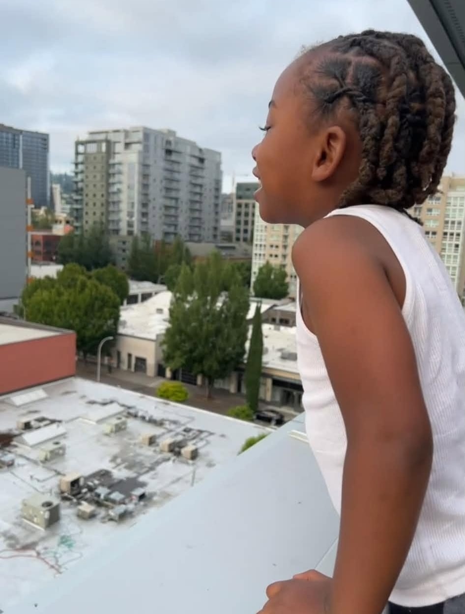 Child enjoying a city view from a rooftop