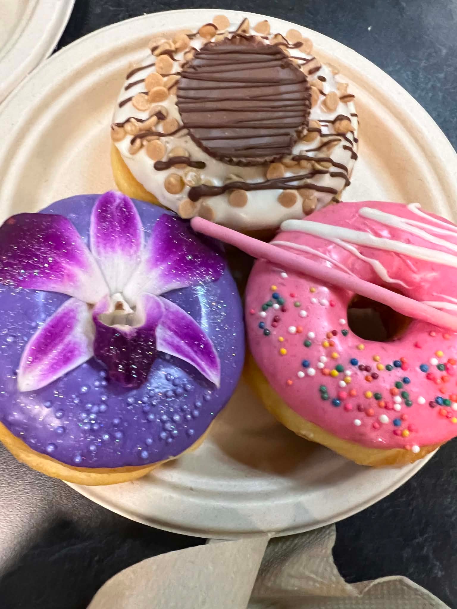 Three colorful decorated donuts on a plate