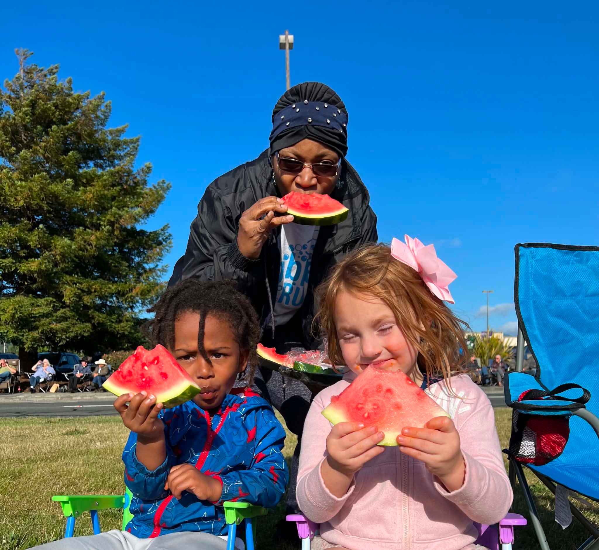 Families enjoying watermelon together at an outdoor gathering