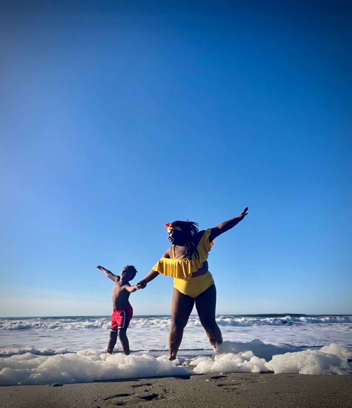 Adult and child enjoying ocean waves together