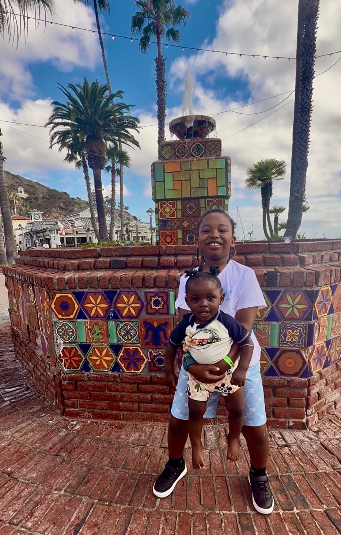 Children posing together by a colorful tiled fountain