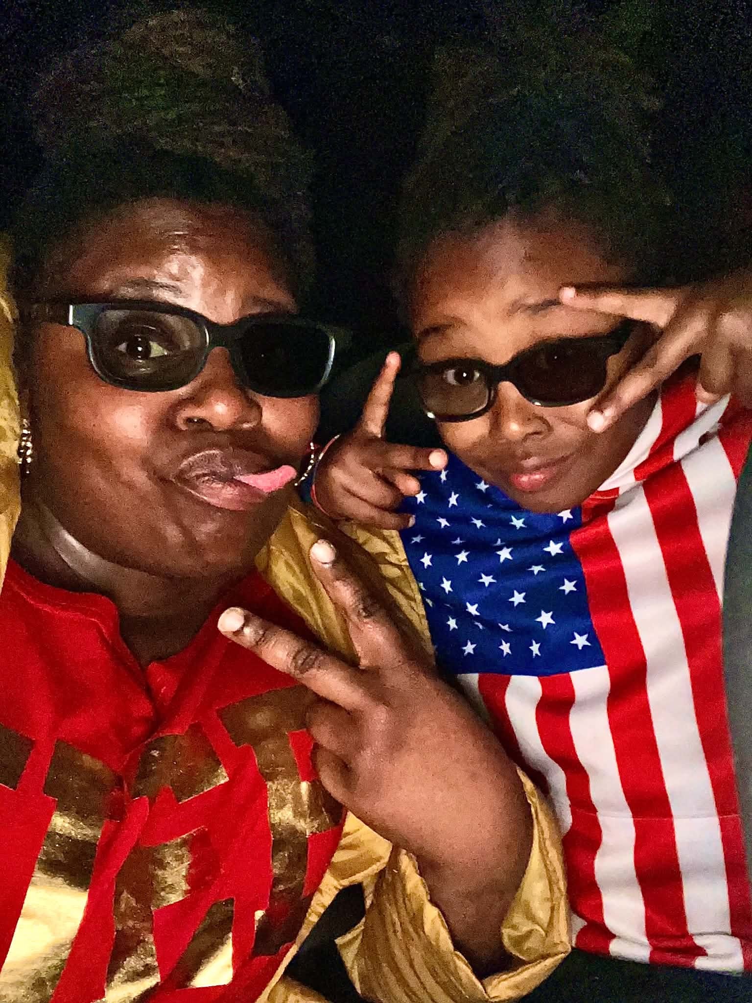 Adult and child sharing a playful moment in sunglasses