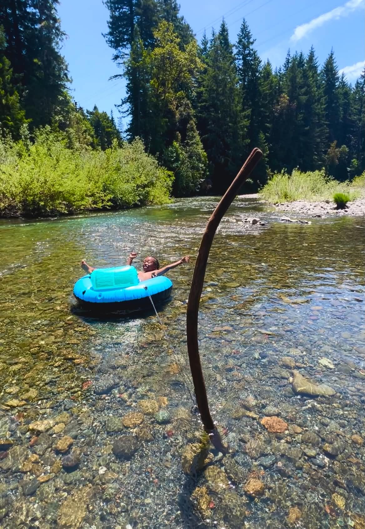 Person relaxing in a blue tube on a clear forest river