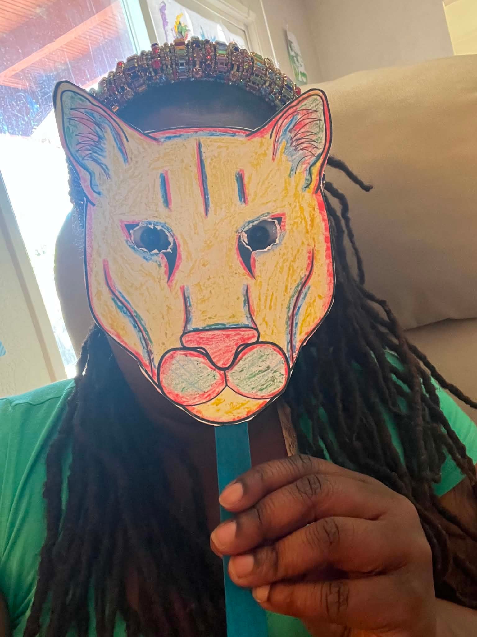 Community member holding a colorful handmade cat mask