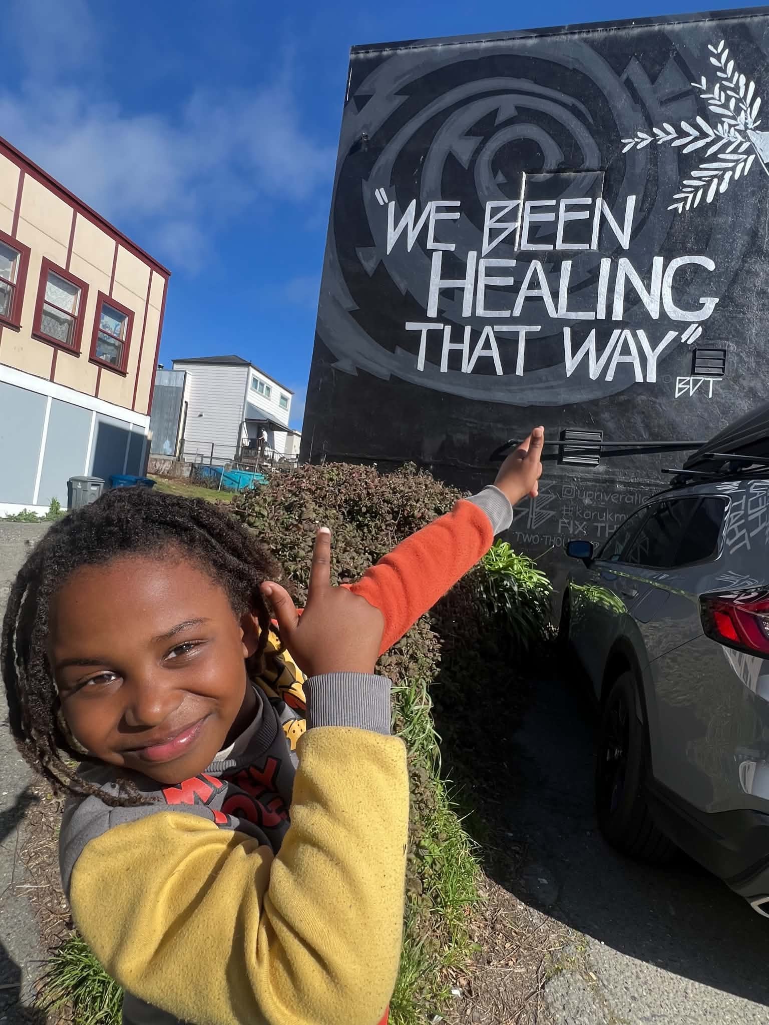 Child pointing to a community healing mural