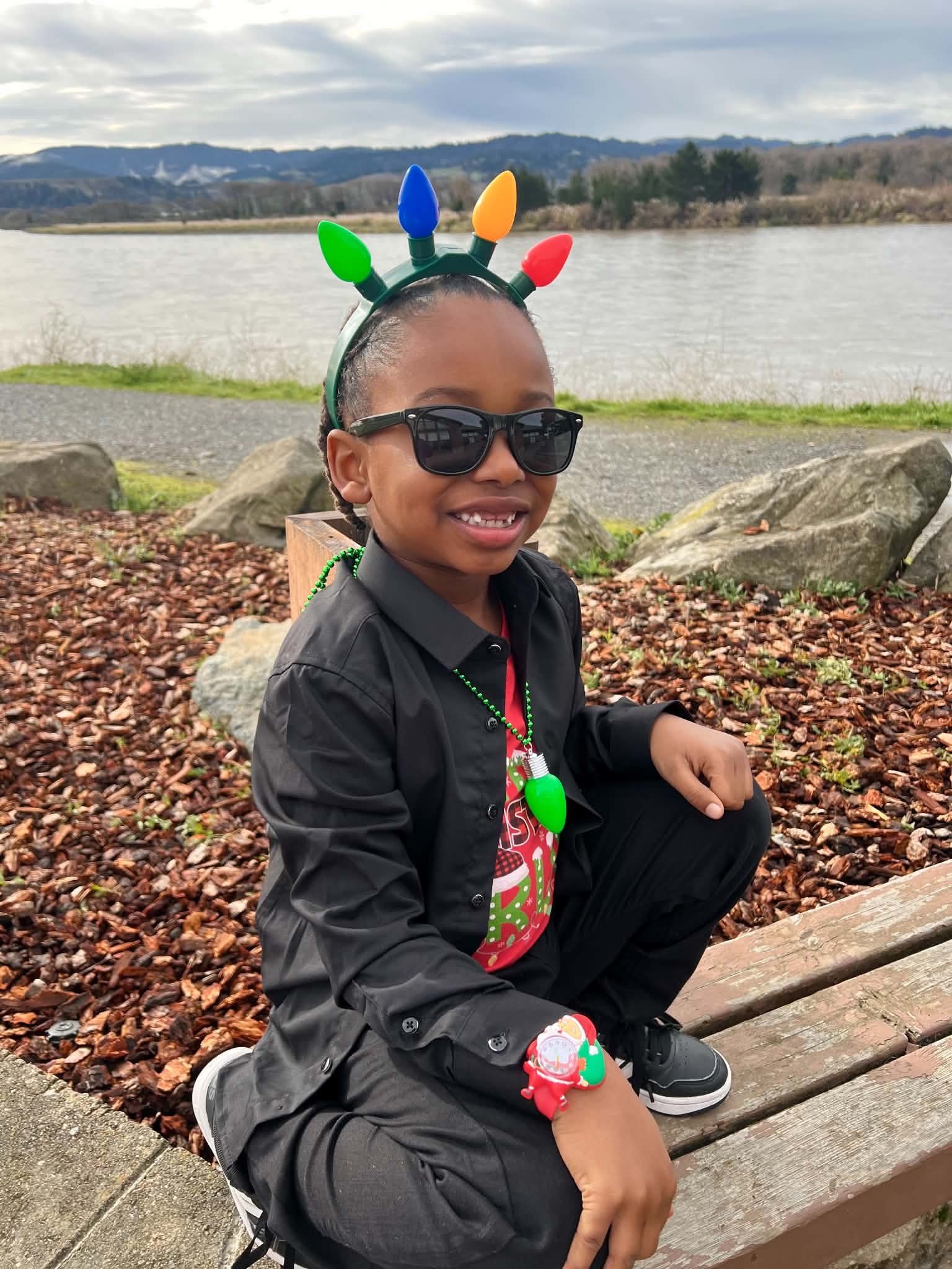 Child wearing festive light-up accessories near the river