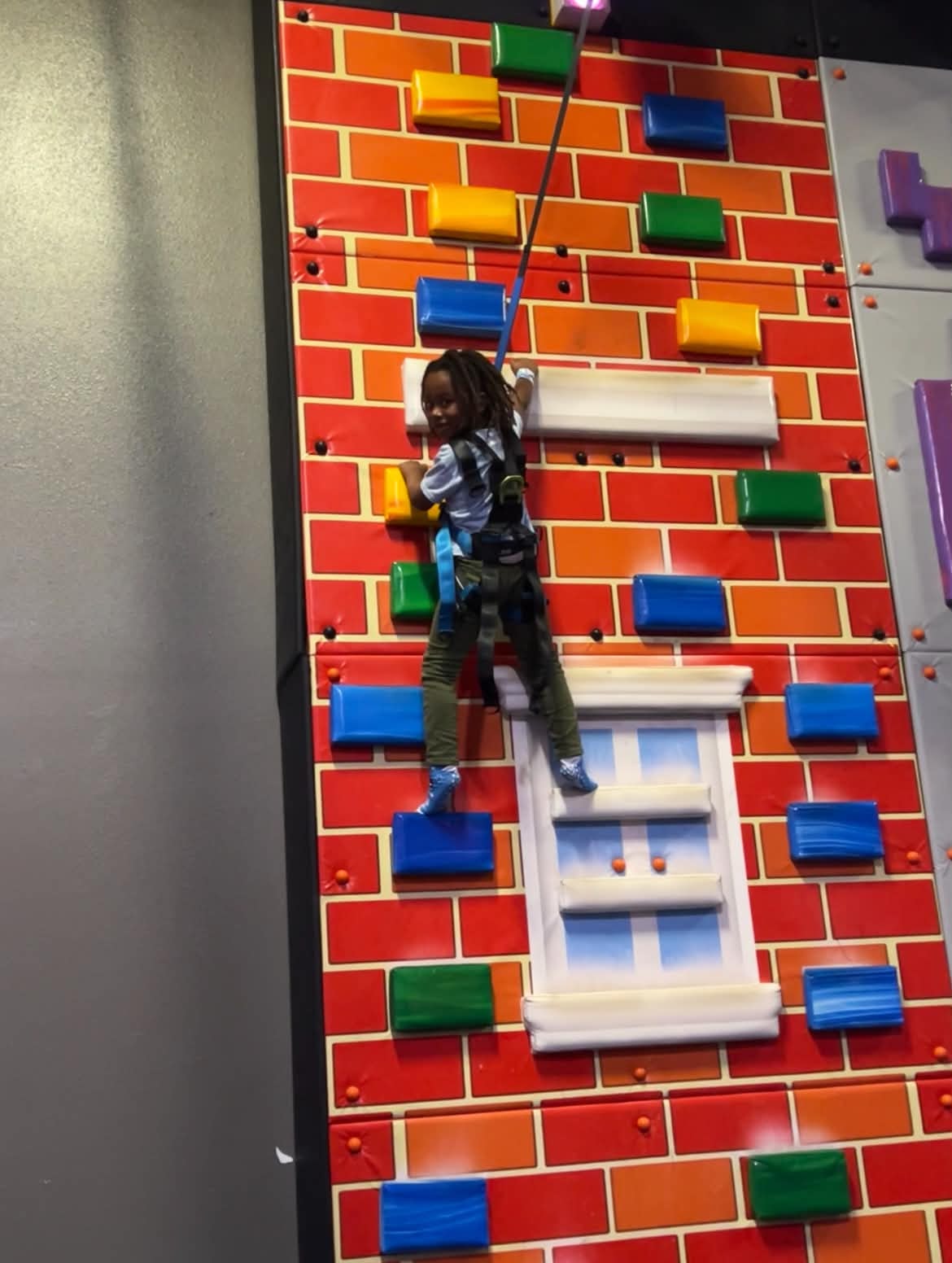 Child climbing a colorful indoor adventure wall