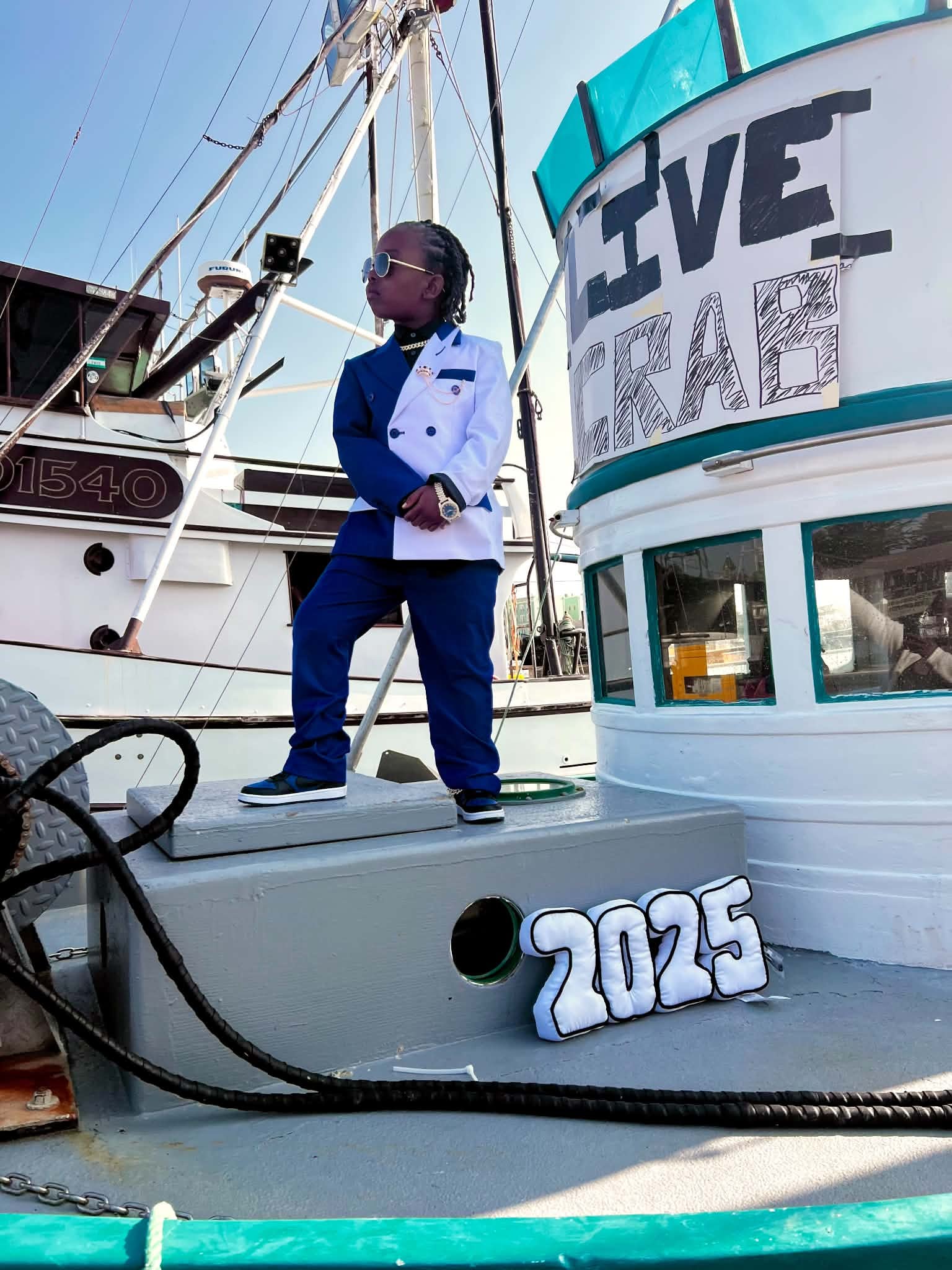 Child in a blue suit posing on a fishing boat
