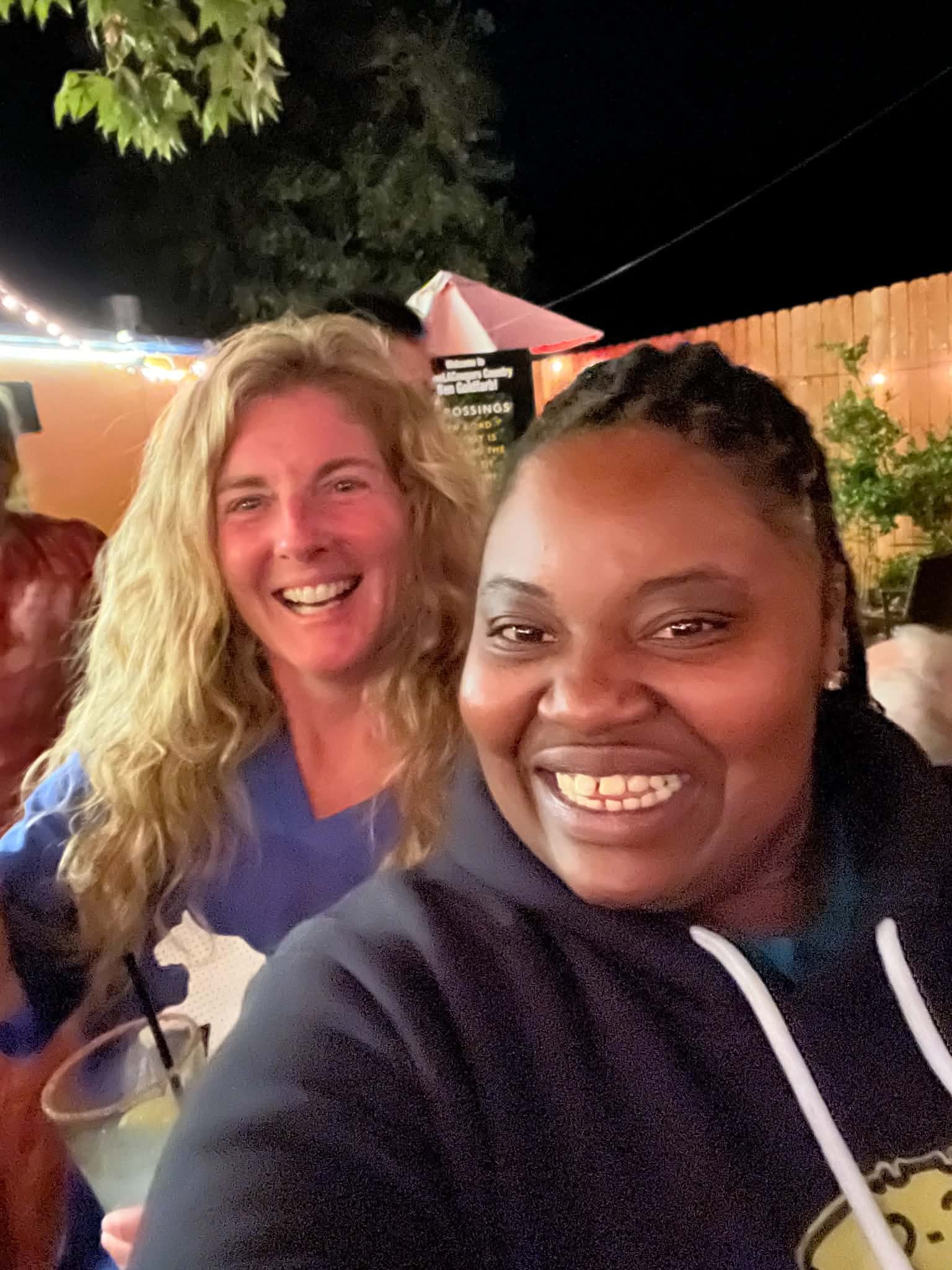 Two friends smiling together at an evening gathering