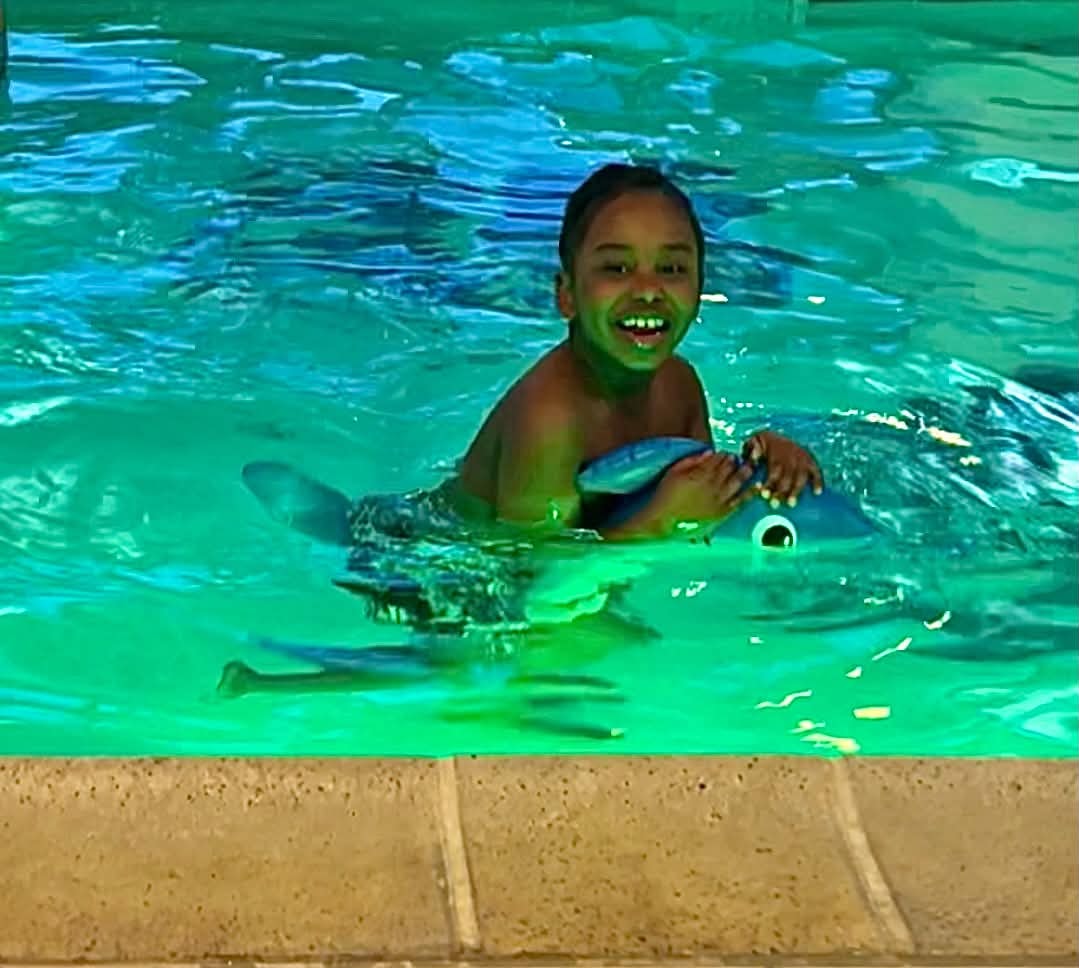 Child enjoying a swim with a crocodile float