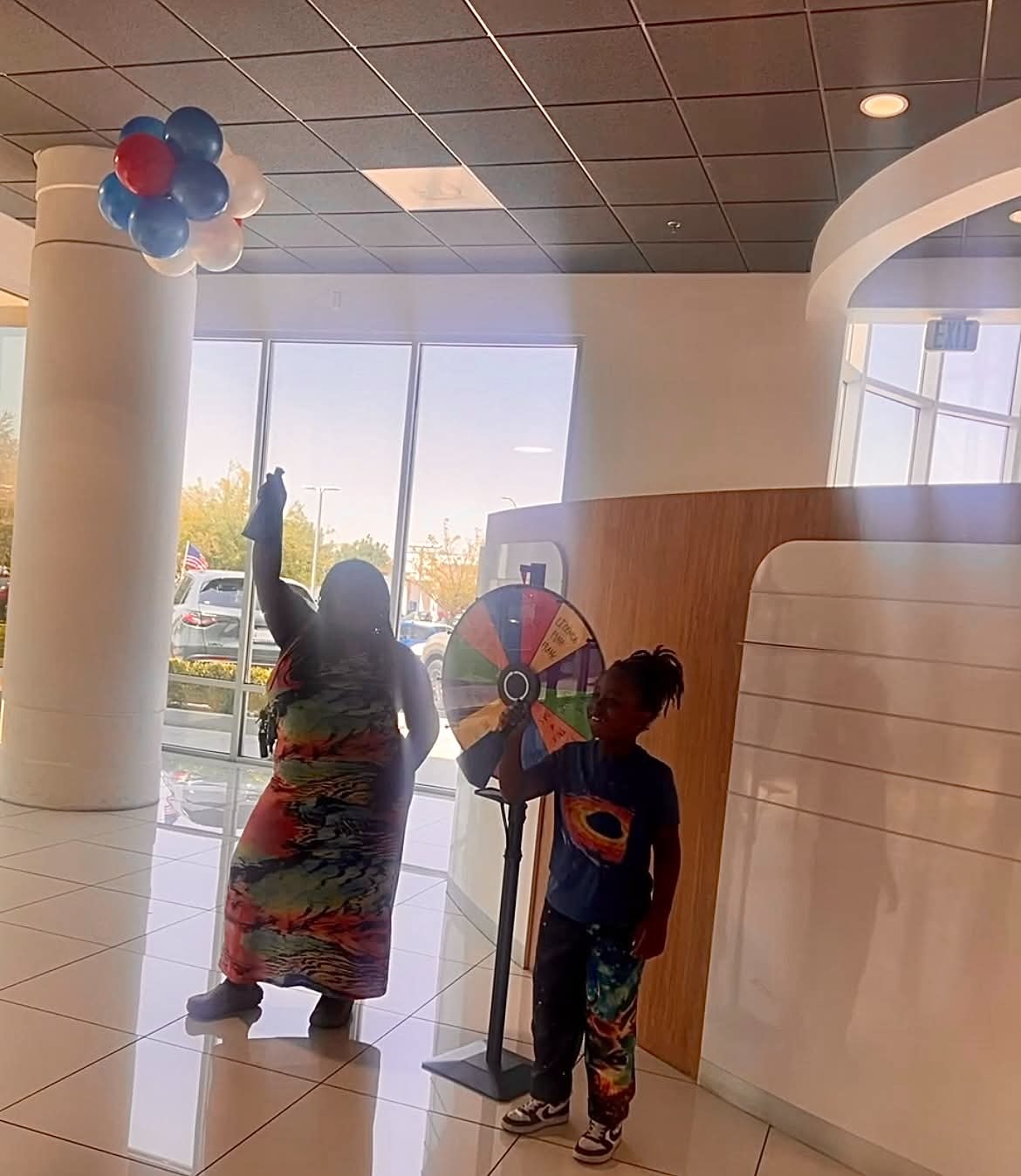 Child and community member beside a colorful prize wheel