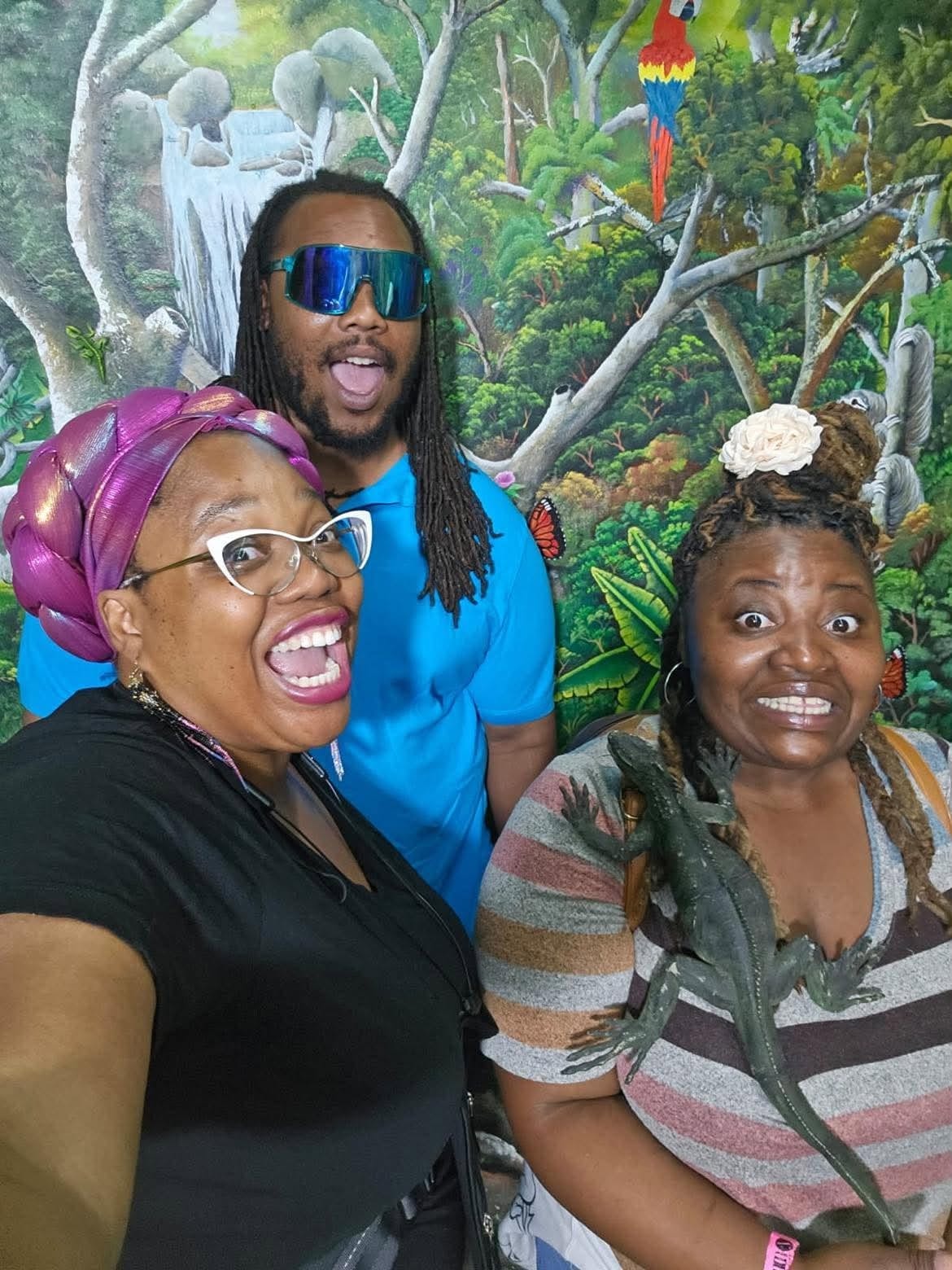 Community group posing in front of a colorful rainforest mural