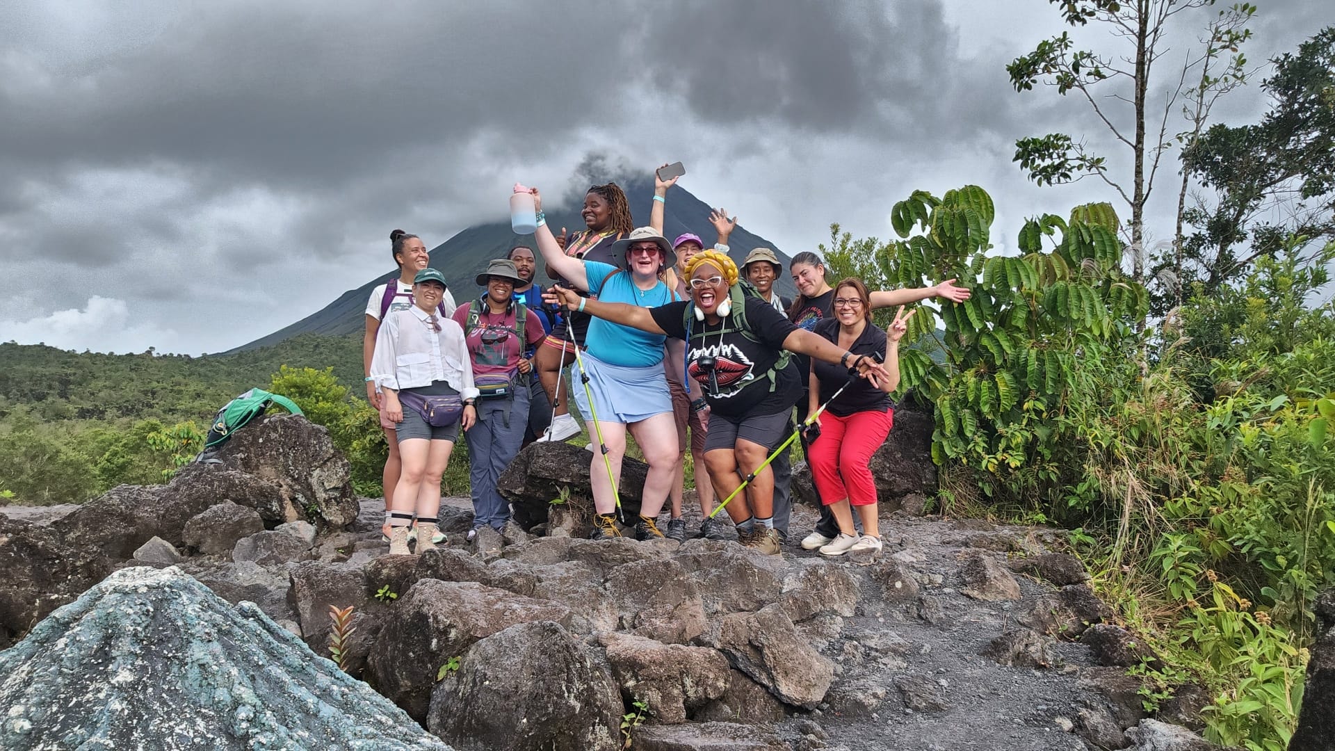Travel group hiking together with a volcano behind them