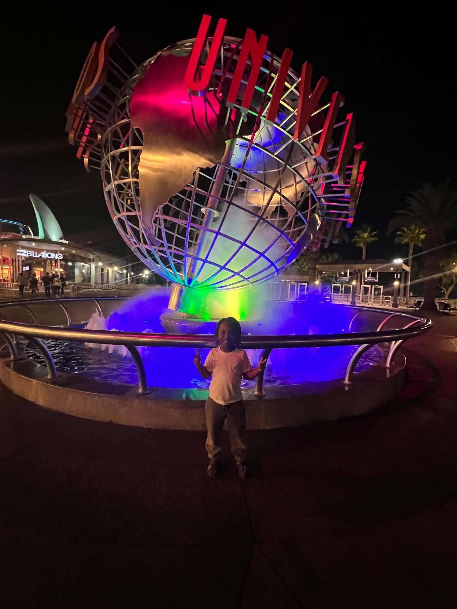 Child visiting the Universal globe fountain at night