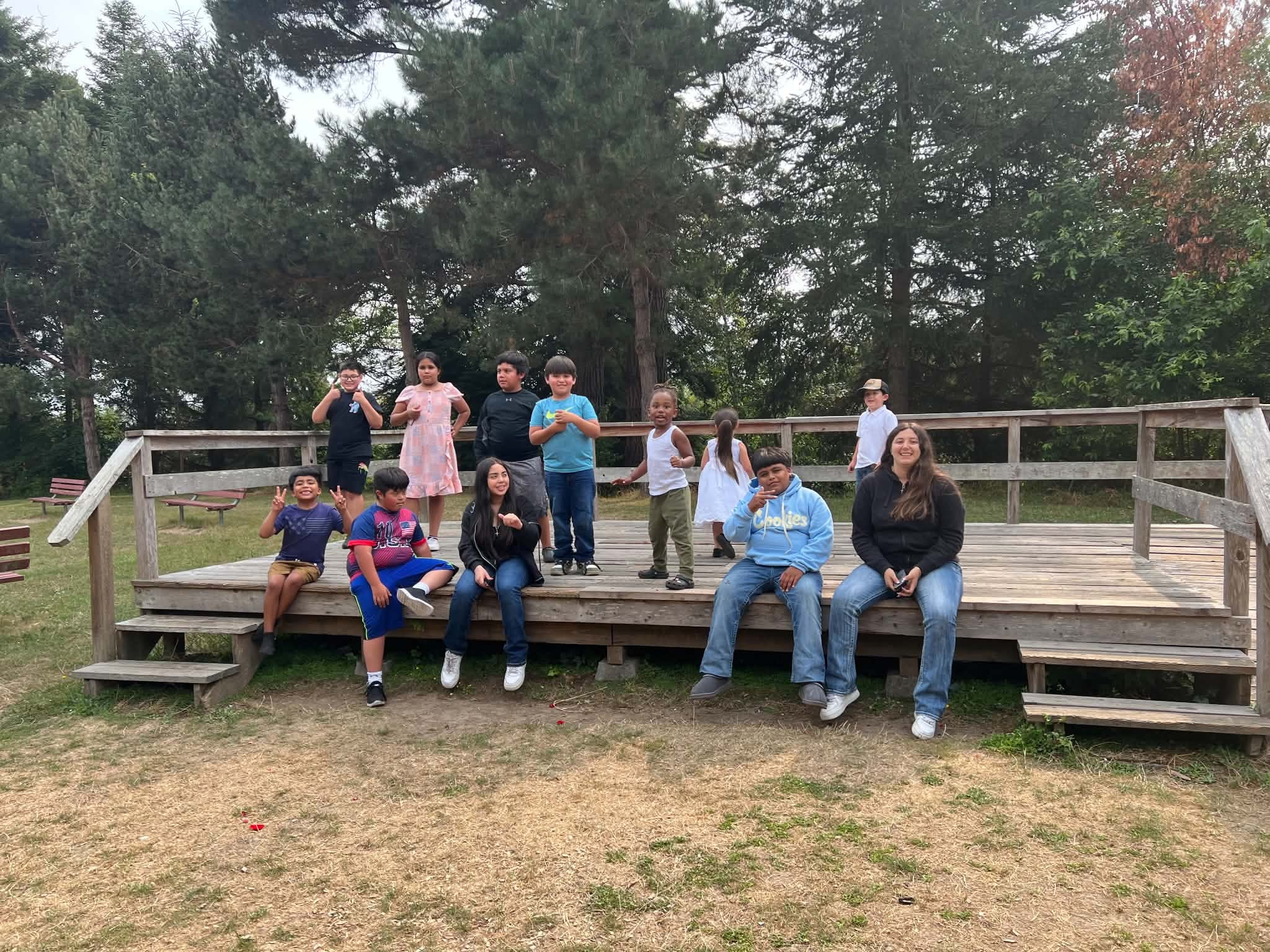 Children and adults gathered outdoors on a wooden platform